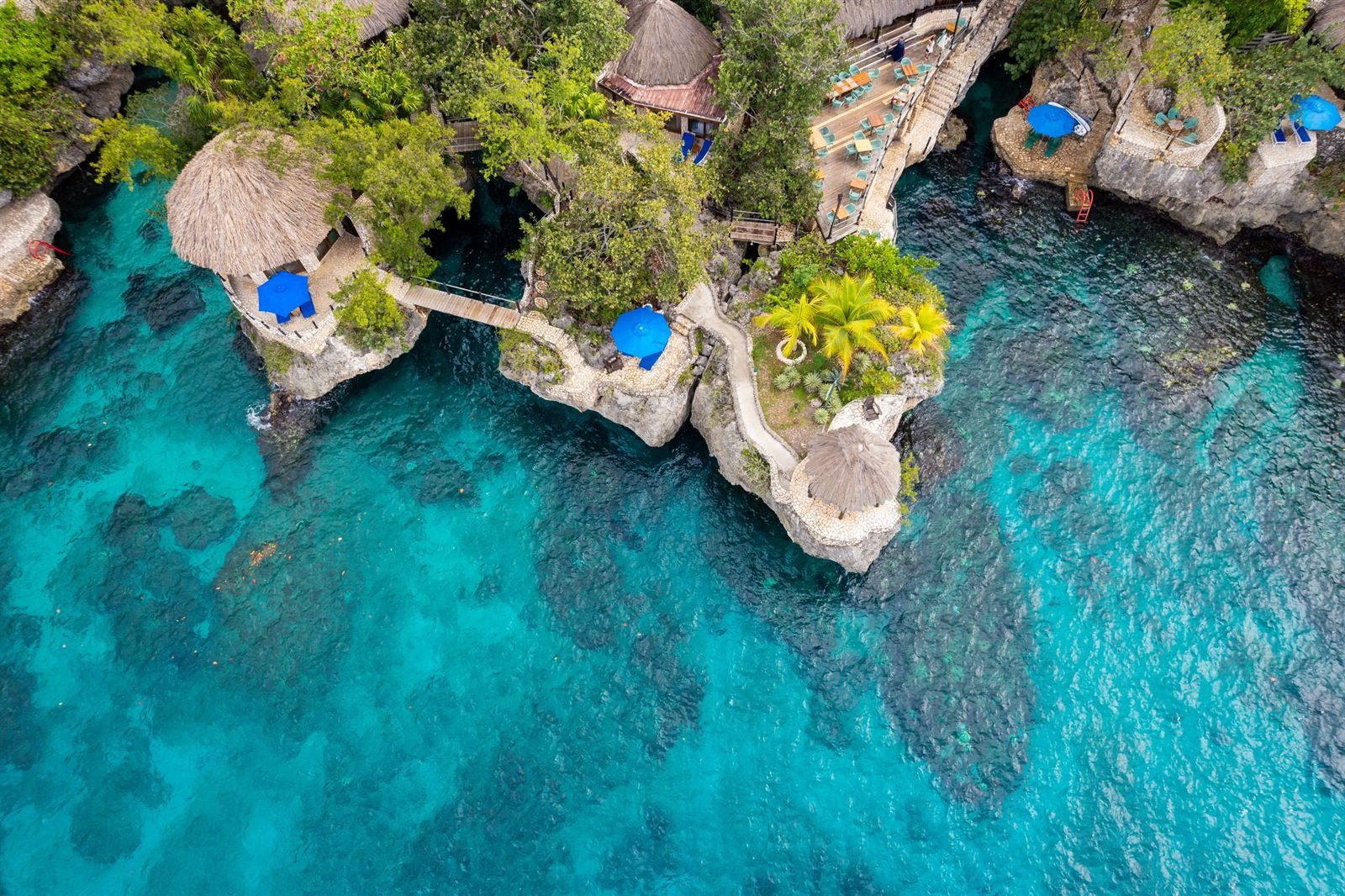 Thatched huts on rocky cliffs above turquoise coves in Negril, one of the things to do in Jamaica