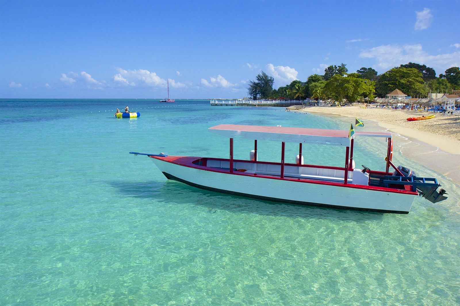 A small boat anchored in clear turquoise water off a beach near Montego Bay, Jamaica